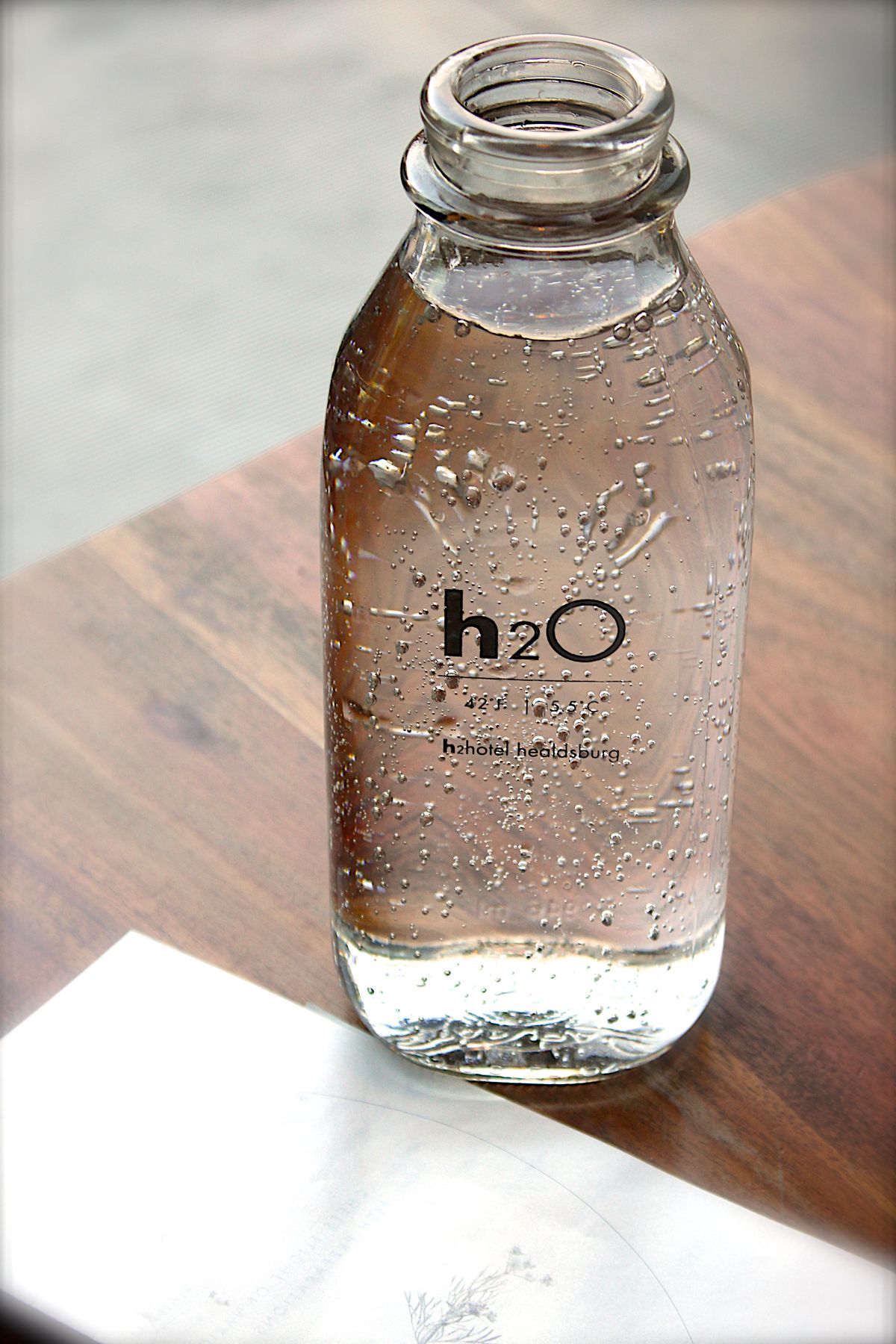 A glass water bottle on a wooden table