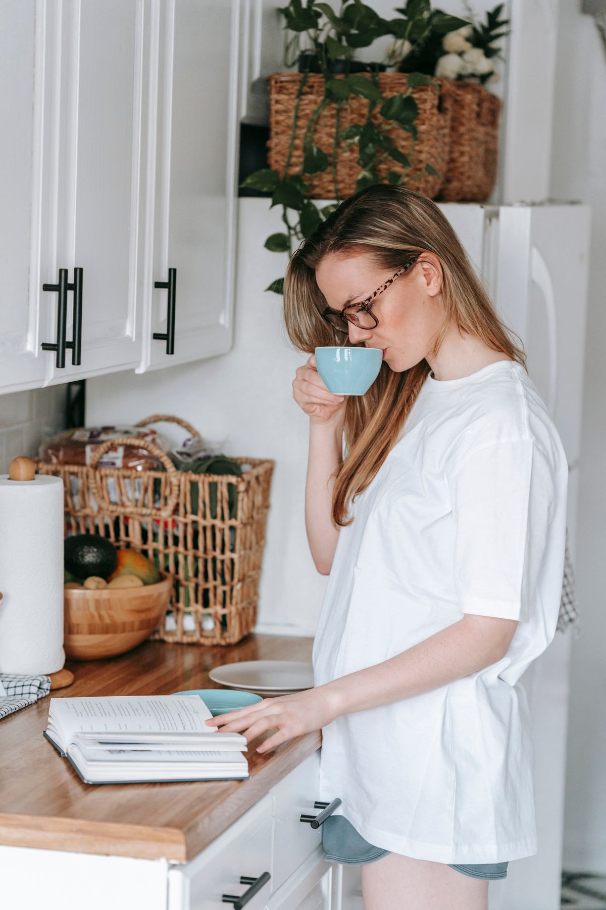 A woman enjoying coffee and a book in a relaxed kitchen setting